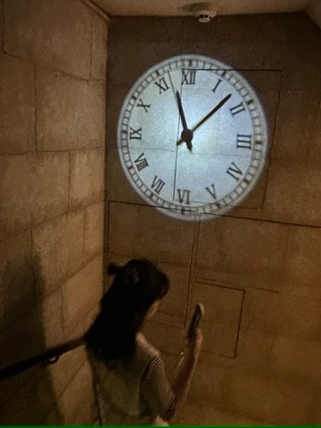 石壁に大時計が投影された薄暗い階段