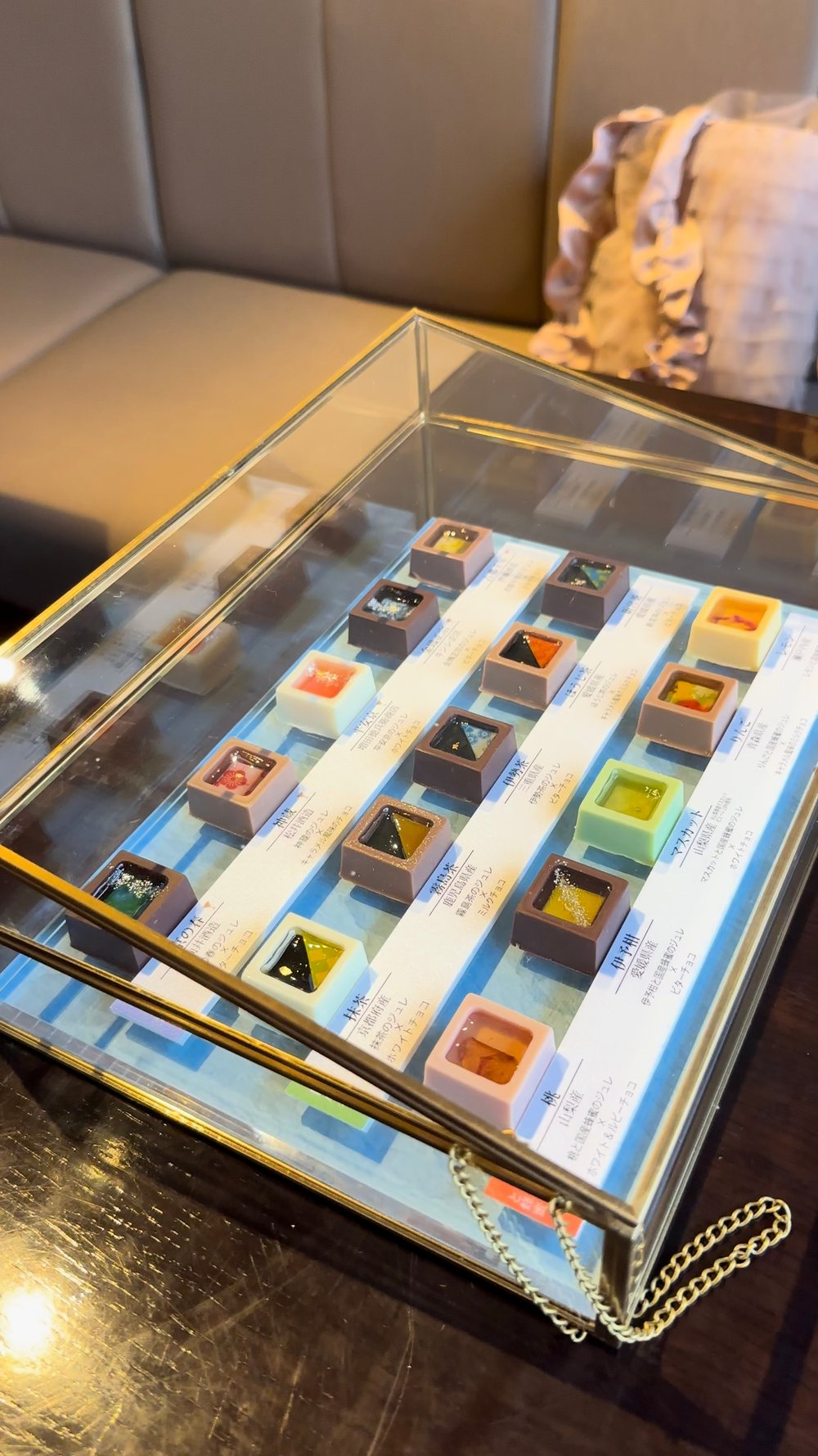 チョコレートが並んだガラスのショーケース。右奥のソファにフリルのついたバッグが写っている